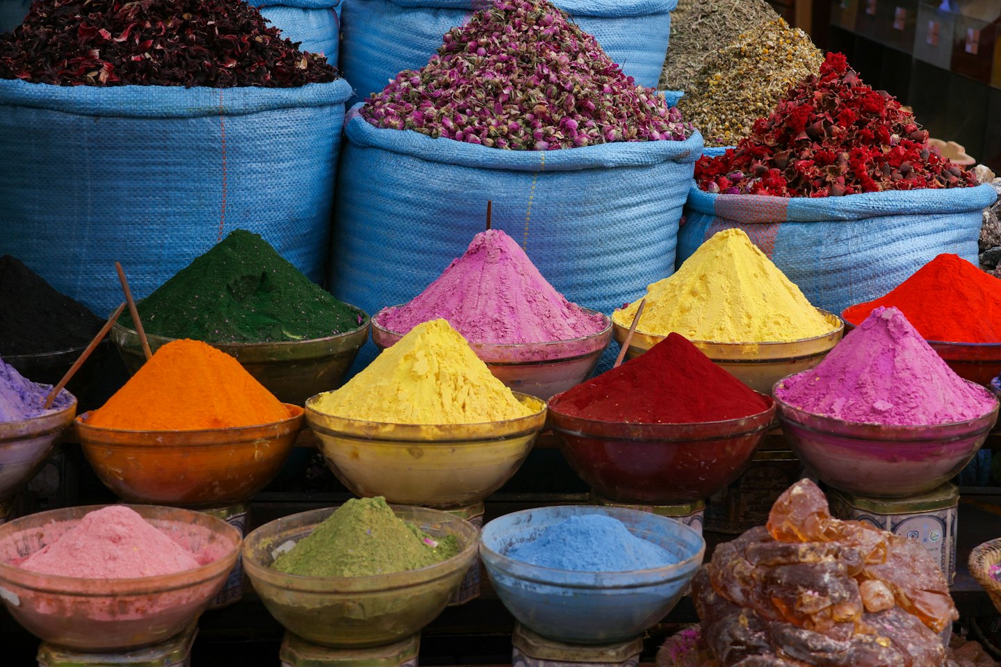 Especias coloridas y hierbas secas apiladas en cuencos de un puesto del mercado.