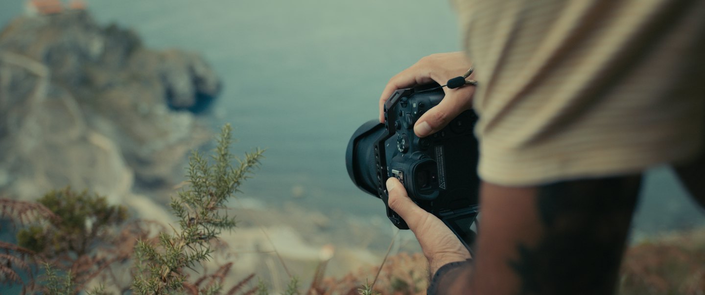 Persona fotografía paisaje costero con cámara profesional.