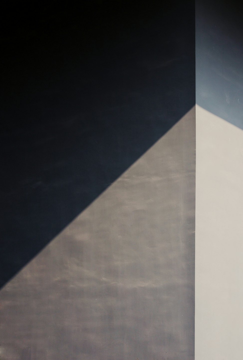 Sombras geométricas caen sobre paredes texturizadas de varios planos.