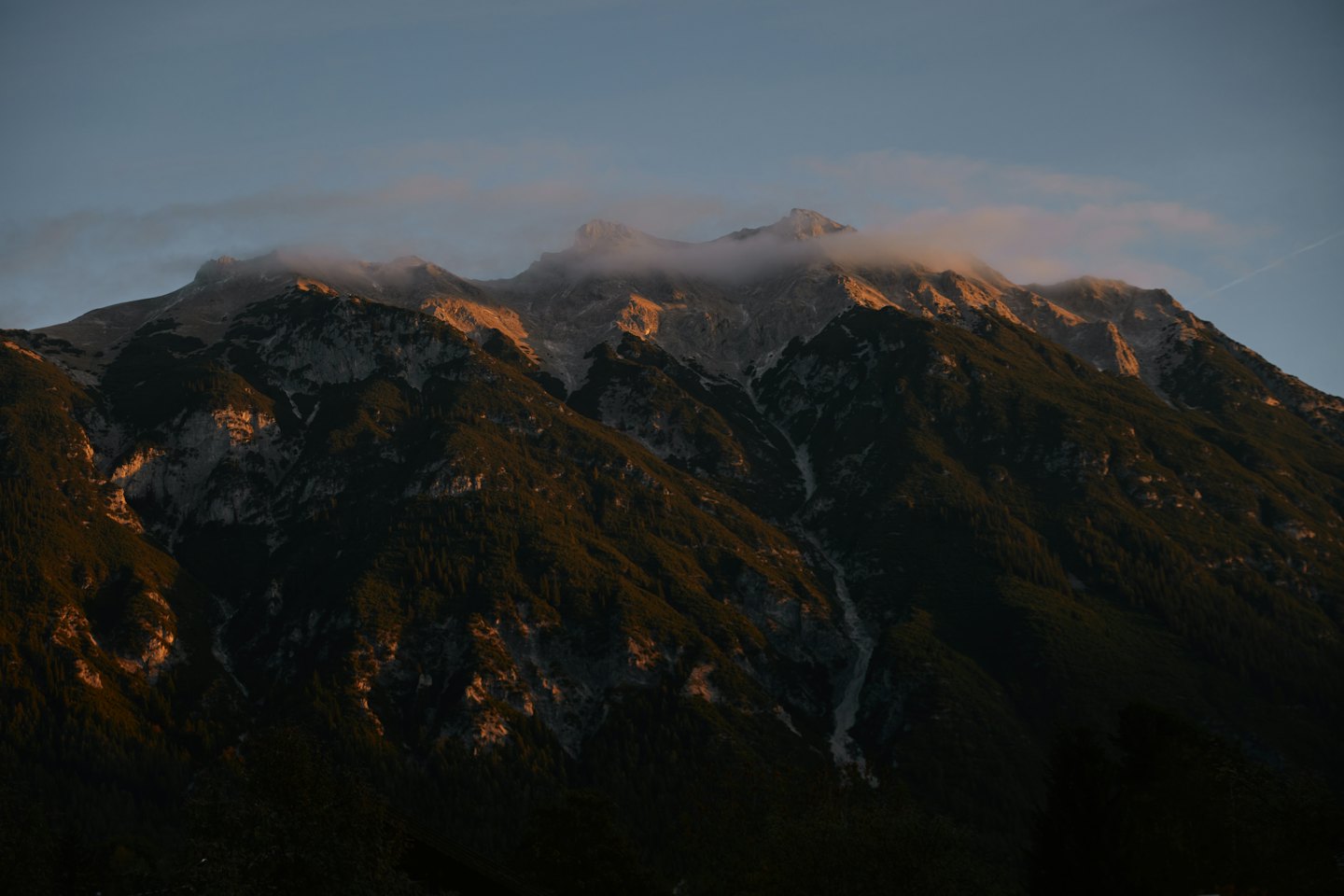 Picos montañosos escarpados brillan con la luz del atardecer.